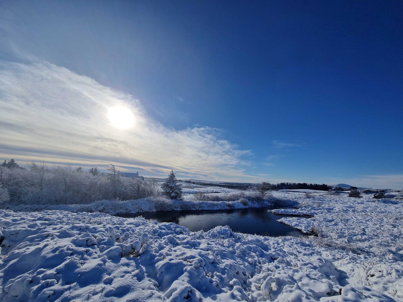 Snow-covered moorland and mountain under a clear blue sky